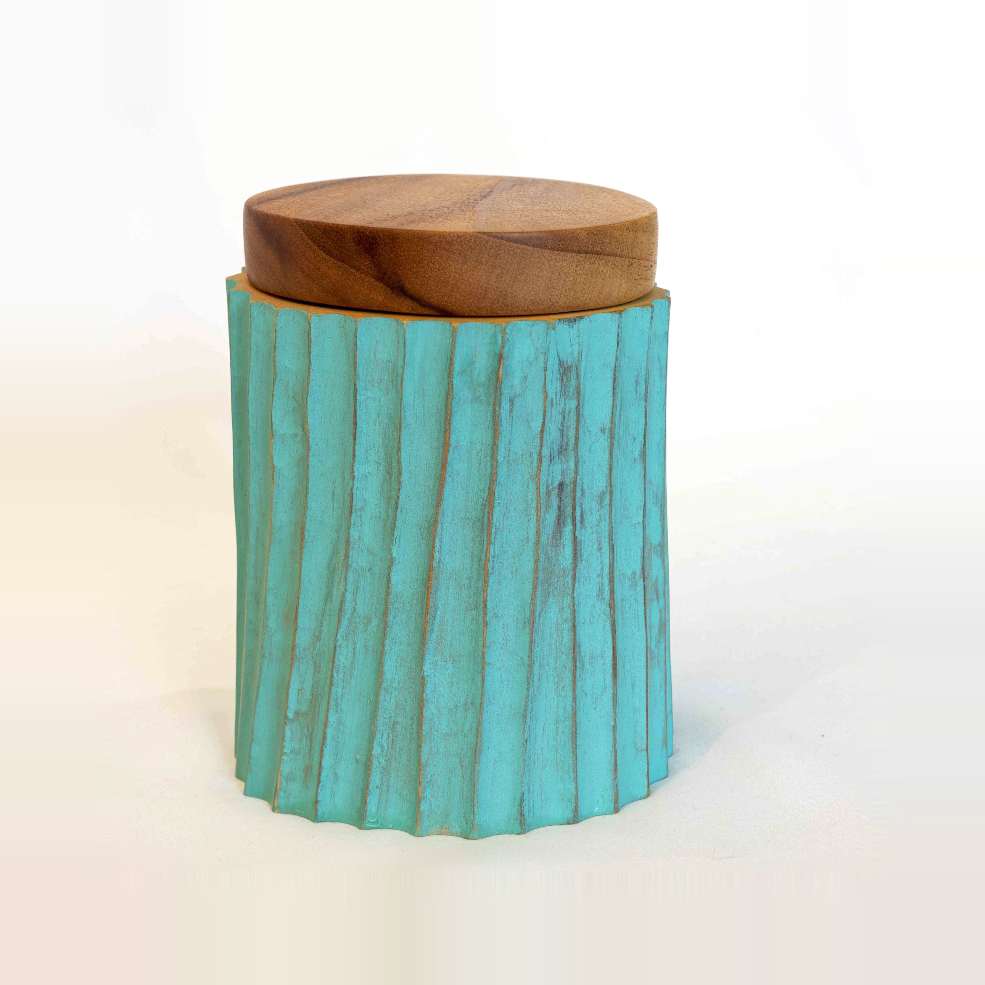 Turquoise sculptural stool detail with carved timber top and textured painted surface.